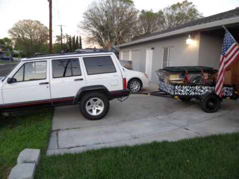 1994 Jeep Cherokee - White 1994 Jeep Cherokee is seen from the side, towing a trailer with a camouflage pattern and an American flag.
