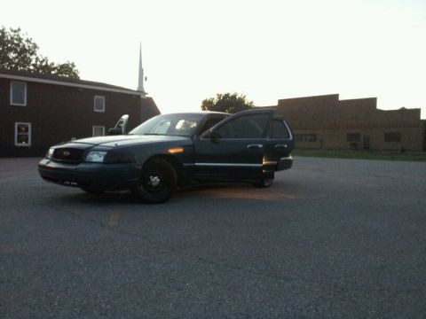 1994 Mercury Grand Marquis - A dark sedan sits in a parking lot with its doors ajar, silhouetted against the sky.