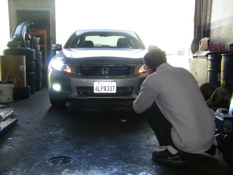 2010 Honda Accord - A photographer crouches to capture the front view of a silver sedan, highlighting its HID headlights and license plate.