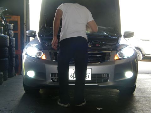 2010 Honda Accord - A person works on a silver sedan with its hood open, showing the front end with lights illuminated.
