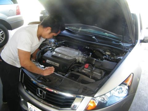 2010 Honda Accord - A mechanic inspects the engine of a silver 2010 Honda Accord.