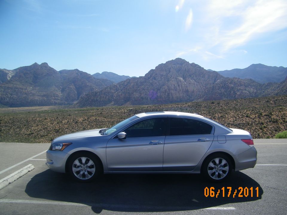 Silver sedan parked on asphalt with mountains in the background