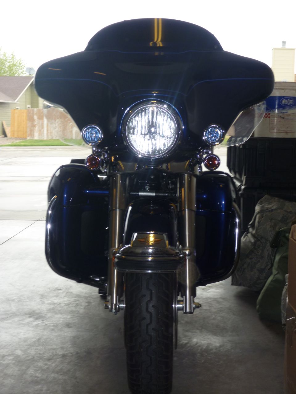 Front view of dark blue Harley-Davidson Electra Glide with fairing, passing lamps, and hard saddlebags in a garage