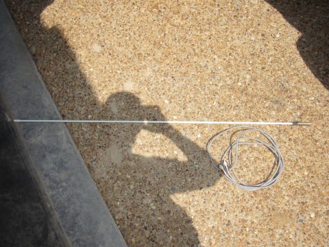 1992 Ford Bronco - A car antenna and its coiled cable are shown on a gravel surface, with a shadow of a person visible.