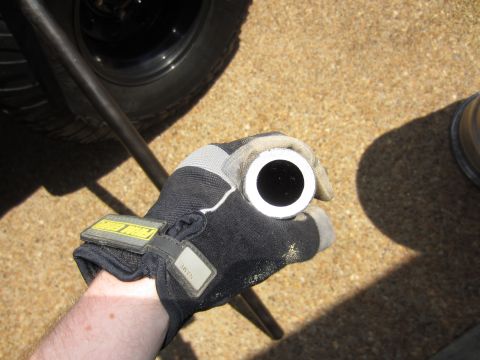 1992 Ford Bronco - A gloved hand holds a metal tube near a vehicle's tire.