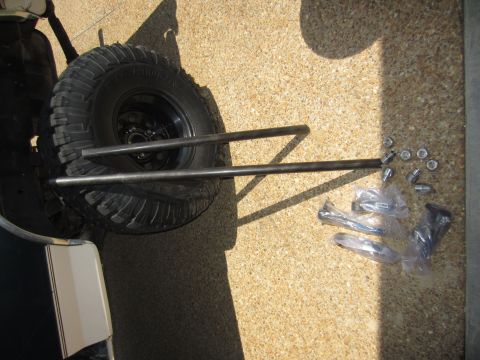1992 Ford Bronco - Parts laid out on a concrete surface, including a spare tire and metal bars.