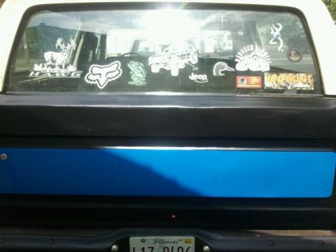 1979 Ford Bronco - This truck's rear window is decorated with various stickers, including outdoor and brand logos.