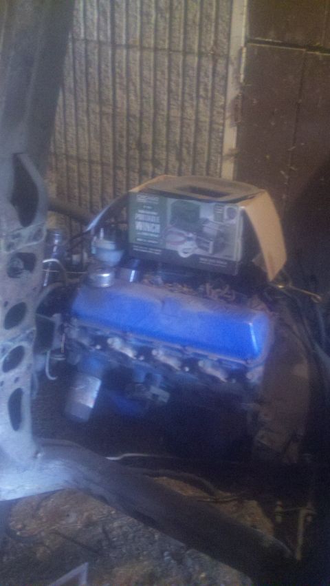1988 Ford Bronco - A blue engine sits in what appears to be a workshop, with a portable winch box resting on its valve covers.