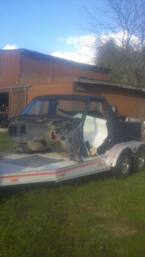 1988 Ford Bronco - The body of a Ford Bronco is being transported on a trailer, with a barn in the background.