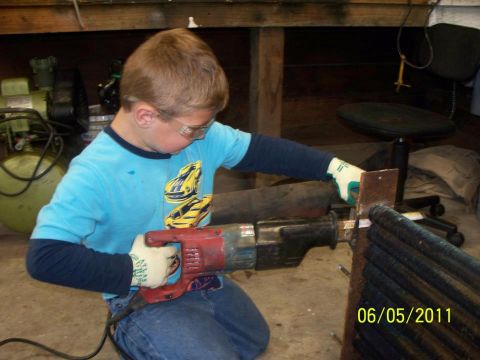 1990 Ford Bronco - A young boy wearing safety glasses and gloves operates a reciprocating saw on metal components.