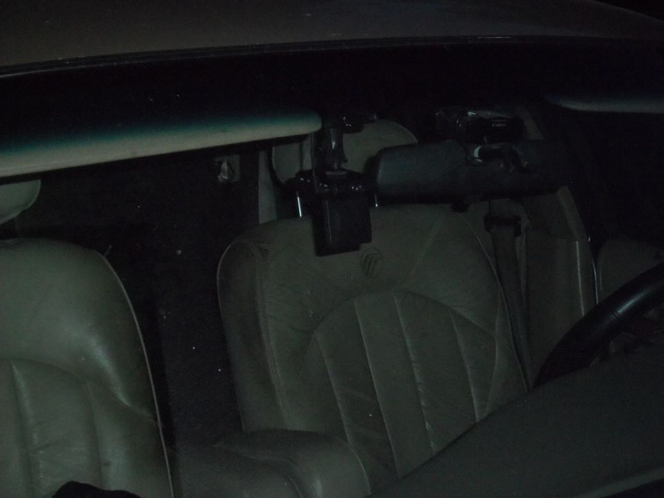 Interior shot of a car showing the passenger seat, driver's seat, rearview mirror, and a dashcam mounted on the windshield