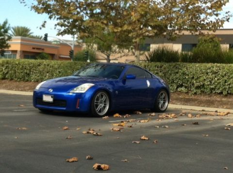 1990 Ford Probe - A blue Nissan 350Z is parked in a lot, with a building and trees in the background.