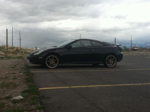 2006 Ford E350 - Side view of a black coupe with aftermarket wheels under a cloudy sky.