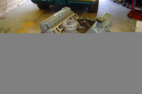 1993 Ford Bronco - Engine block with valve covers removed, revealing internal parts and a yellow cap on one cover.