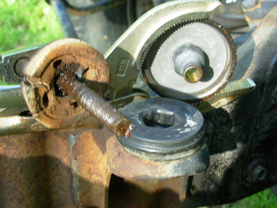 Rusty body mount with greasy stud and rubber bushing held by locking pliers