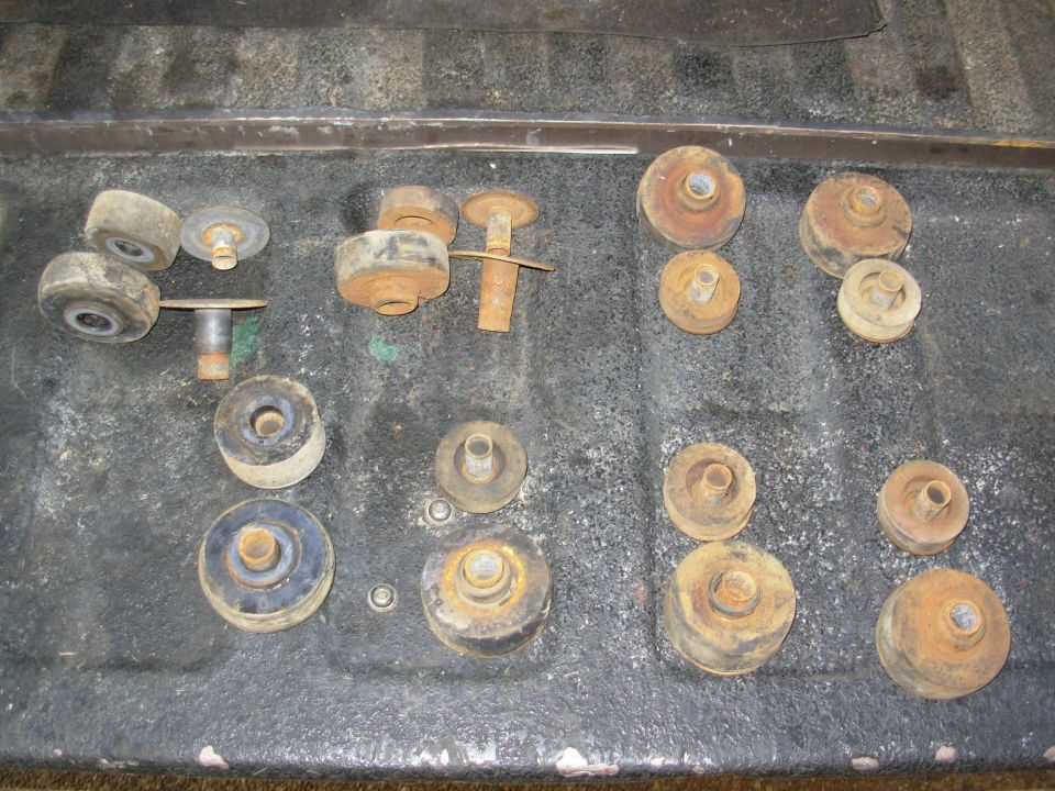 Assortment of worn and rusty rubber body mount bushings arranged on a dark surface