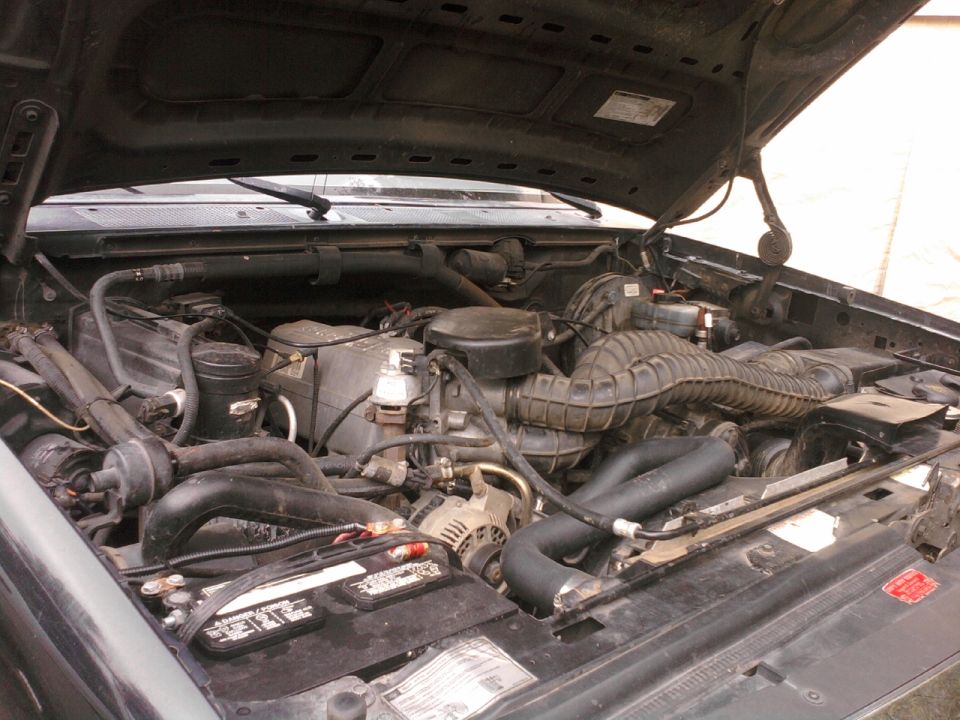 1994 Ford Bronco engine bay with V8 engine, battery, and air intake visible