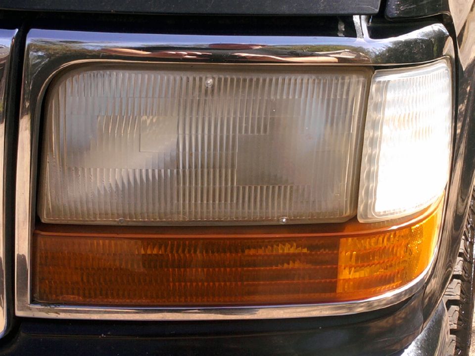 Close-up of a 1992 Ford Bronco headlight assembly with chrome trim