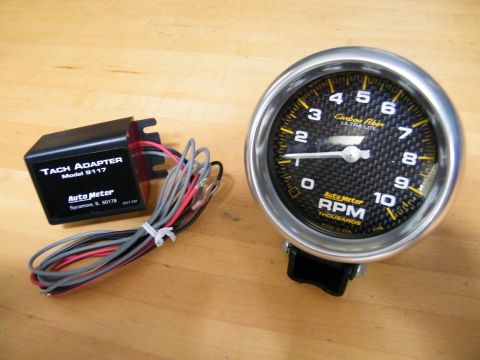2004 Ford Crown Victoria - A tachometer and its adapter are displayed on a wooden surface, ready for installation.
