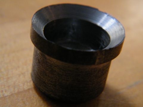 2004 Ford Crown Victoria - A machined metal part with a textured cylindrical body and a beveled opening is shown on a wooden surface.