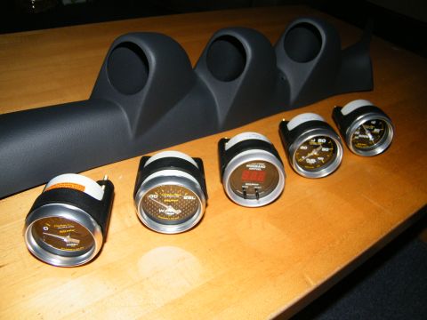 2004 Ford Crown Victoria - A black gauge pod and several automotive gauges are laid out on a wooden table.