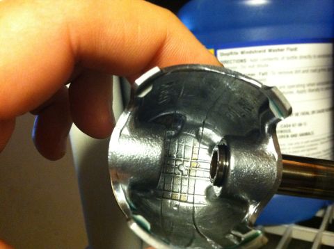 1981 Garelli Rally Sport - Damaged piston with internal grid markings. Blue bottle in background has text.