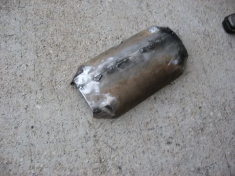 1994 Ford Bronco - A section of exhaust pipe with visible welds rests on a concrete surface.