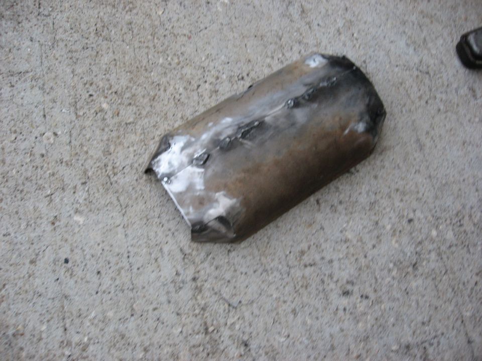 Welded section of exhaust pipe lying on a concrete surface