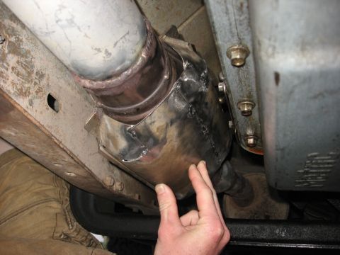 1994 Ford Bronco - Close-up view of a vehicle's exhaust system, focusing on a catalytic converter and its protective shield.