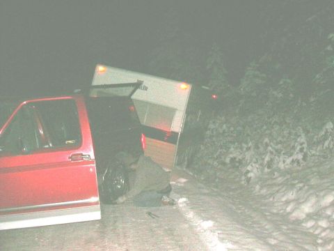 1991 Ford Bronco - Pickup truck and trailer stuck on a snowy road at night.