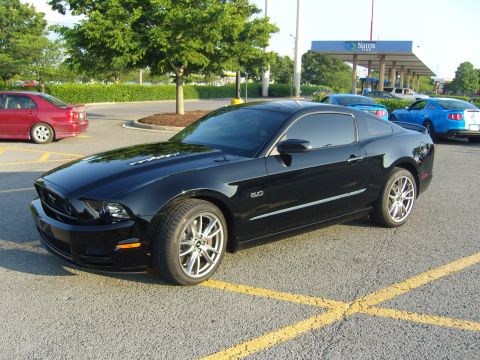 2007 Ford Mustang - A black Ford Mustang coupe, likely a 2010 model, is parked in a lot with other vehicles visible.