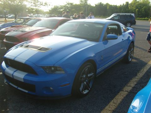 2007 Ford Mustang - A blue Ford Mustang with racing stripes is parked at an outdoor car meet.