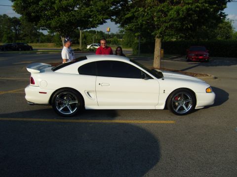 2007 Ford Mustang - A white coupe with a spoiler is parked on asphalt. Another red car is visible in the background.