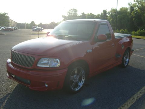 2007 Ford Mustang - A red Ford F-150 SVT Lightning pickup truck is parked in a lot during the day.