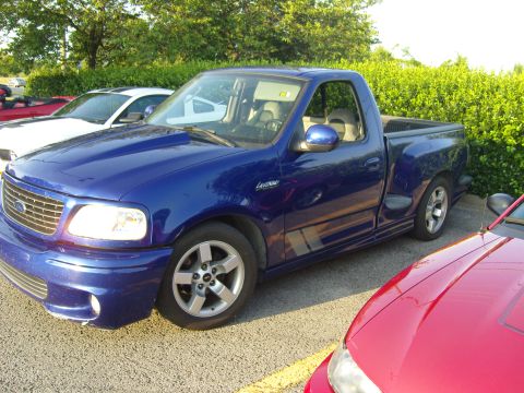 2007 Ford Mustang - A blue Ford F-150 SVT Lightning pickup truck is parked in a lot.