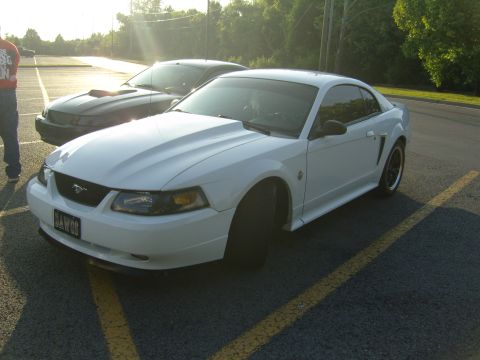 2007 Ford Mustang - A white Ford Mustang is parked in a lot with another car behind it, under a bright sky.