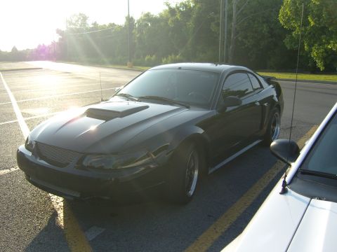 2007 Ford Mustang - A black Ford Mustang is parked in a lot next to another vehicle.