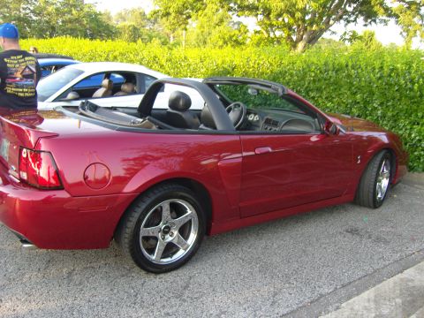 2007 Ford Mustang - Red convertible sports car parked outdoors, with another vehicle visible behind it.