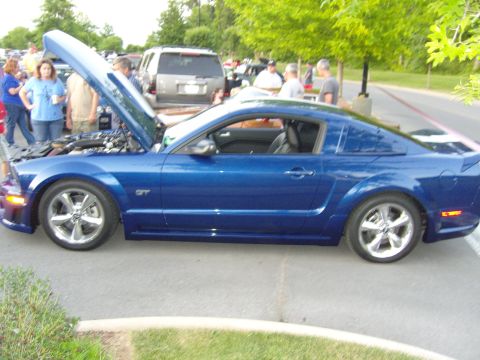 2007 Ford Mustang - A blue Ford Mustang GT is parked with its hood open at an outdoor car meet.
