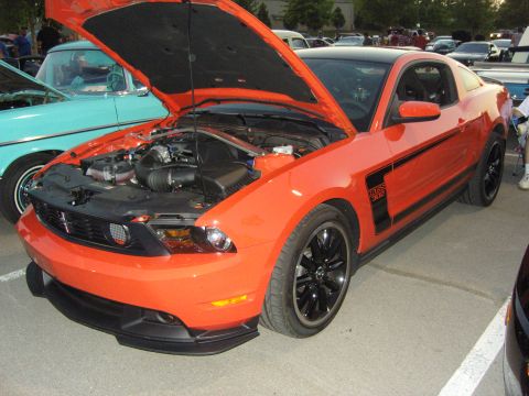 2007 Ford Mustang - An orange 2012 Ford Mustang Boss 302 is displayed with its hood open, revealing the engine bay and front-end details.