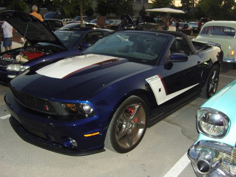 2007 Ford Mustang - Blue 2007 Ford Mustang convertible with racing stripes parked next to other cars.