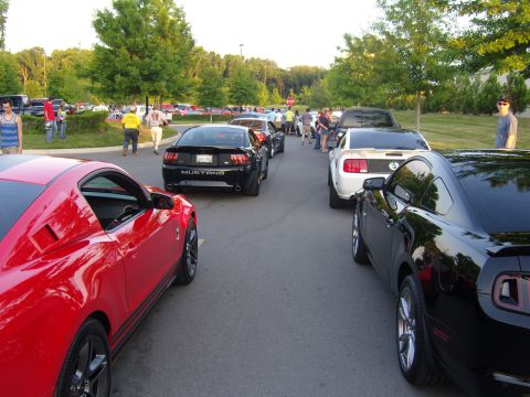 2007 Ford Mustang - Several Ford Mustangs are gathered in a parking lot, with red, black, and white models visible.