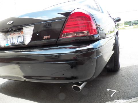 2003 Ford Crown Victoria - Detail of black sedan rear bumper shows the SVT badge, EVIL VIC license plate and a single chrome tailpipe.