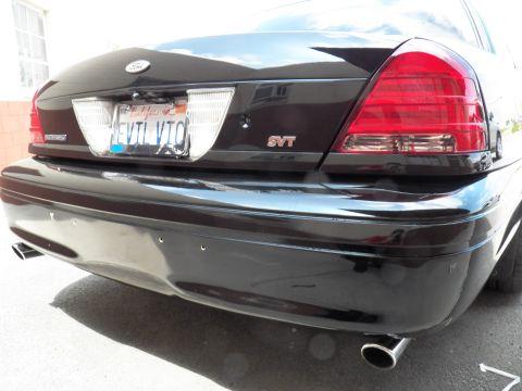 2003 Ford Crown Victoria - Black sedan tail close-up with INTERCEPTOR trim, SVT badge, EVIL VIC plate and twin chrome exhaust tips.