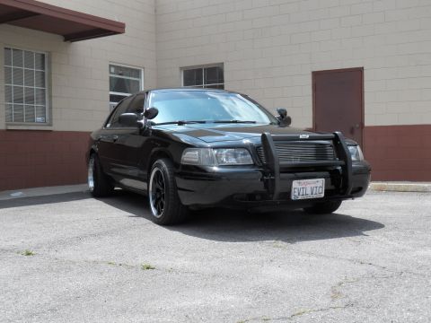 2003 Ford Crown Victoria - Black sedan front three-quarter showing billet grille, grille guard, spotlight and EVIL VIC plate.