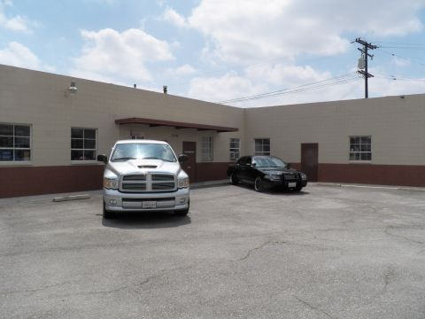 2003 Ford Crown Victoria - Front three-quarter shot of a silver Dodge Ram with a black sedan parked at a beige warehouse.