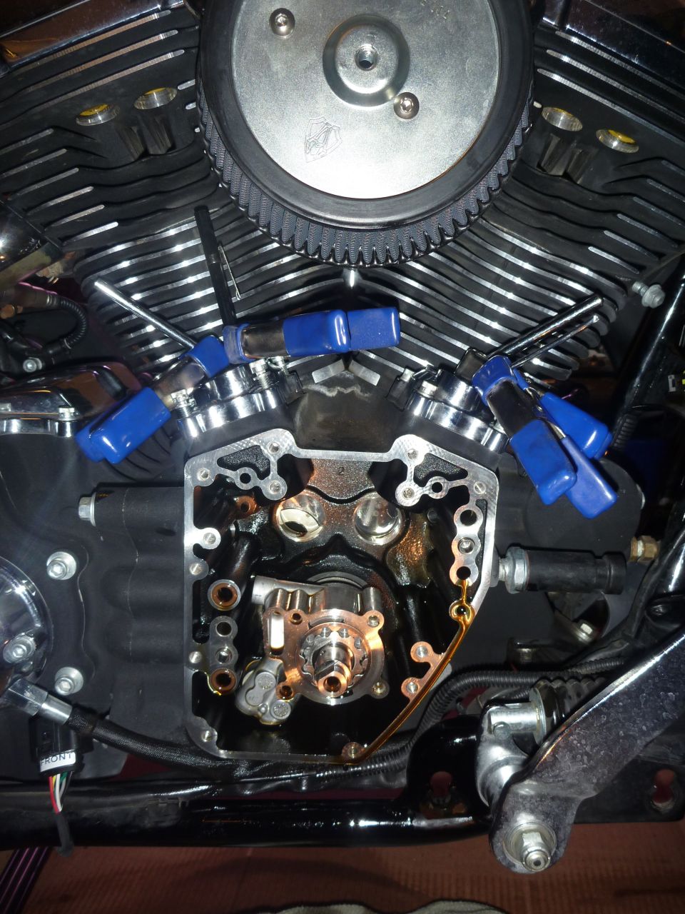motorcycle engine with valve train exposed, blue clips holding parts