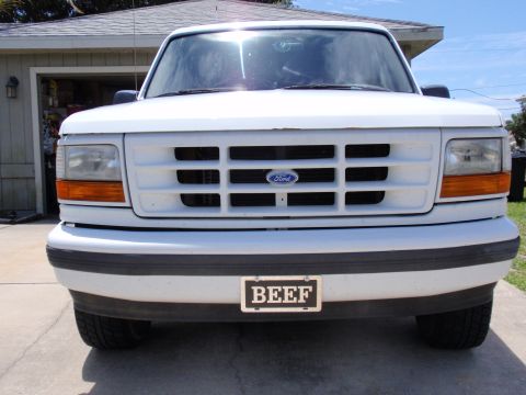 1995 Ford Bronco - This is a front view of a white Ford truck, its grille and a custom license plate.