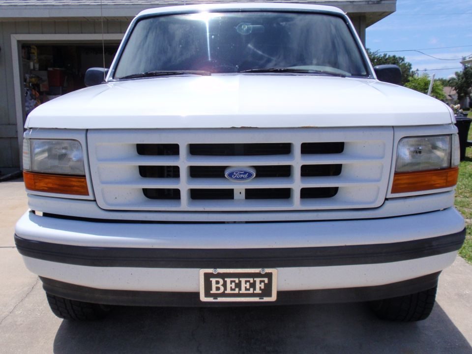 White Ford truck front view with horizontal grille and a license plate reading BEEF