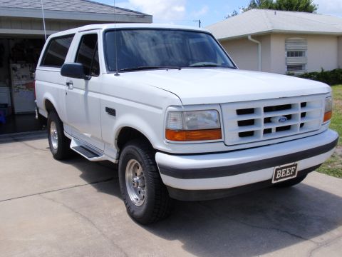 1995 Ford Bronco - White Ford Bronco SUV parked in a driveway, showing its front 3/4 view with a custom license plate.